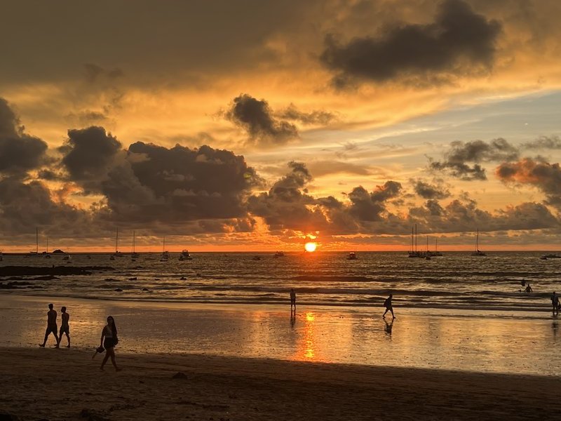 Golden sunset on Costa Rica's Pacific coast with boats and beachgoers